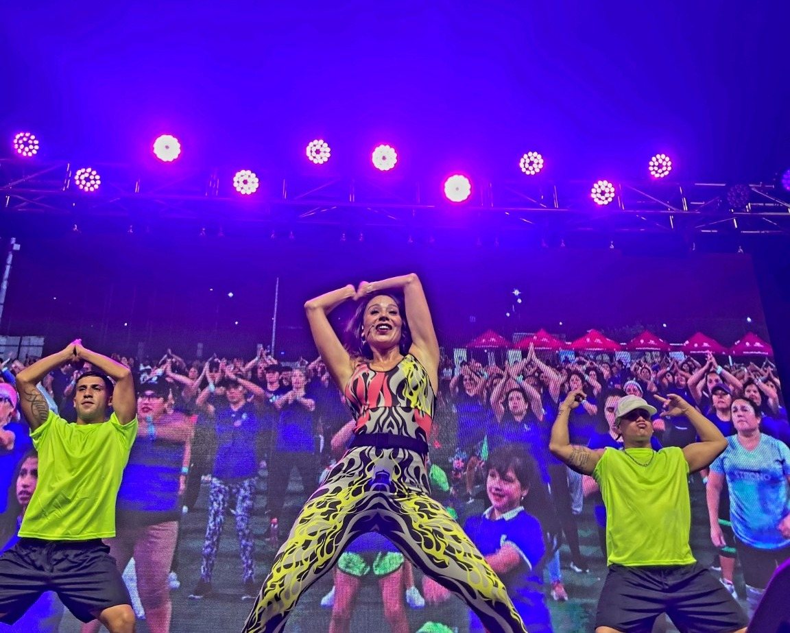 Yamna Lobos liderando un evento masivo de baile y Zumba en escenario, con público participando